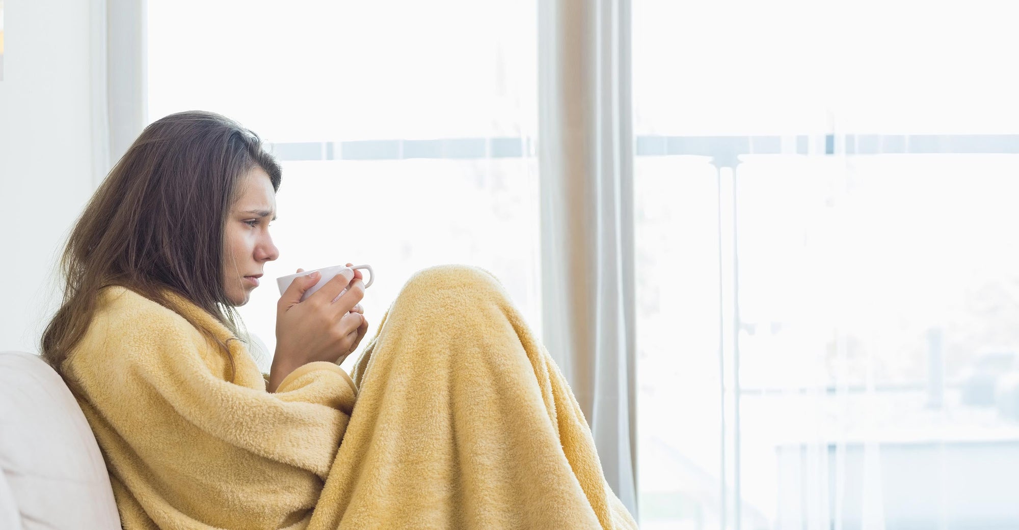 A sick woman is sipping a cup of tea