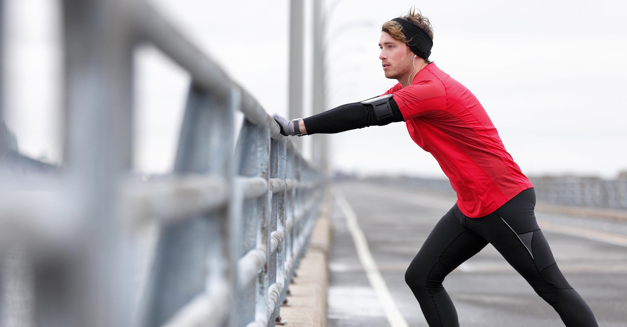 Man exercising, leaning against freeway divider and taking a rest