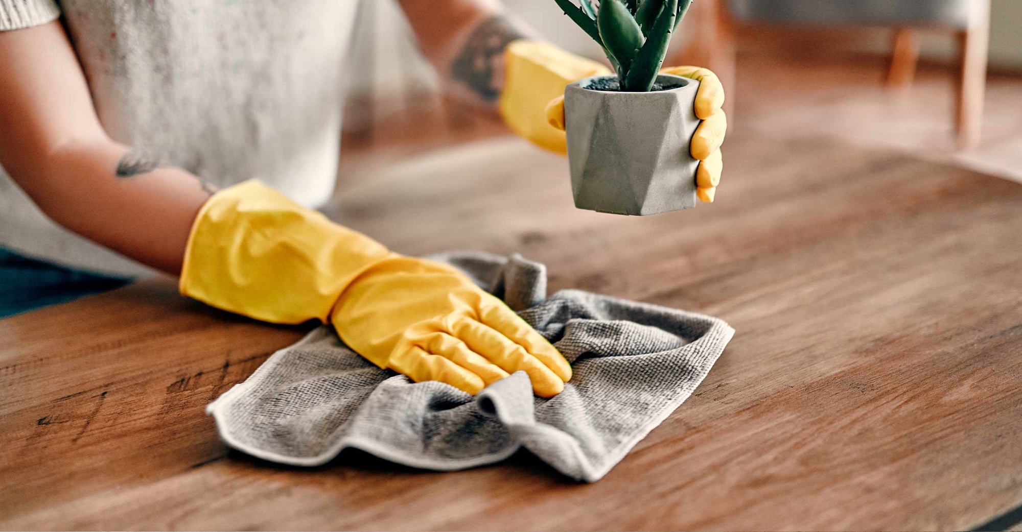woman with cleaning glove wiping dust from table